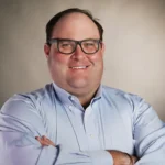 Smiling man in glasses with arms crossed